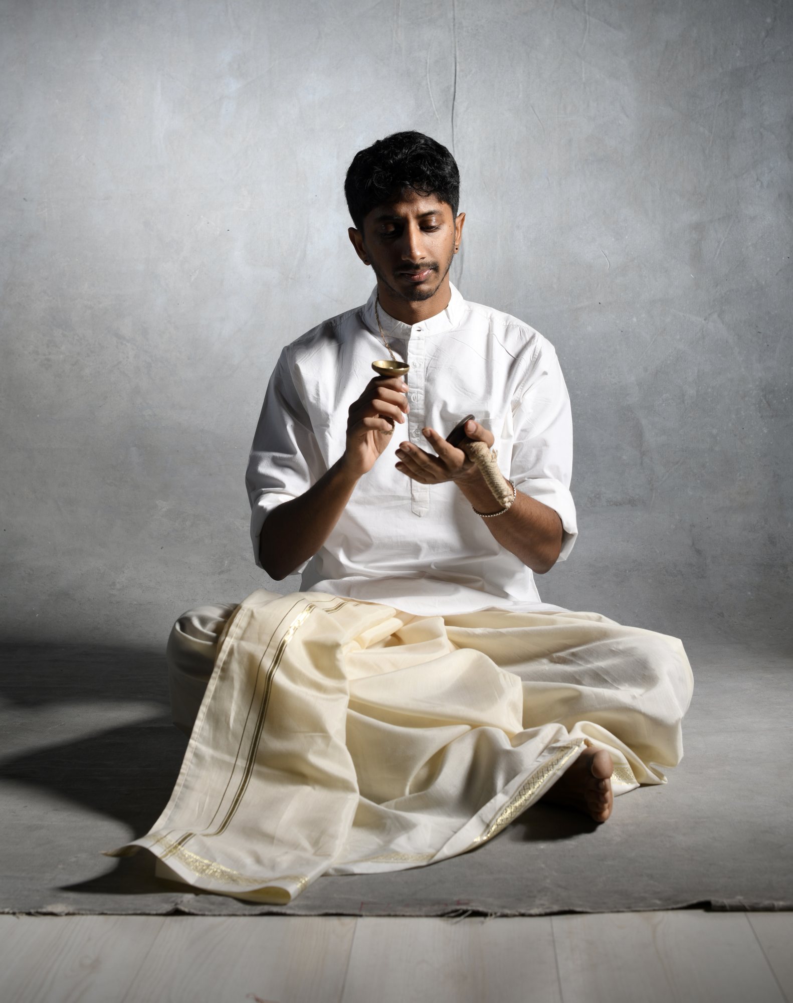Vivek Ramanan seated in white, holding cymbals